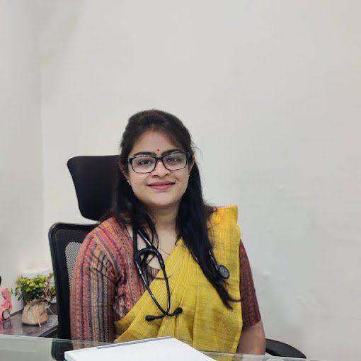 Dr. Krati Mehta Chandak seated at her clinic desk, wearing a yellow saree and stethoscope, smiling warmly, symbolizing compassionate women’s healthcare in Indore.